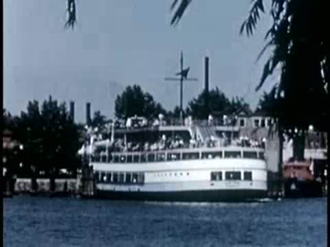 Large passenger ferry boat traveling on water near wooded shore, 1940s.