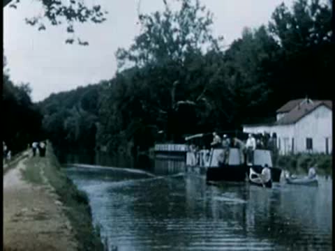 Canal scene with boats and buildings on shore, 1940s film style