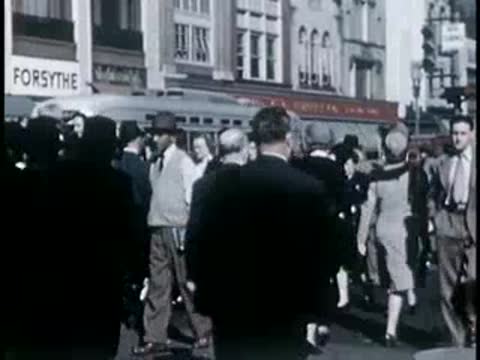 Pedestrians walking down a busy downtown sidewalk, 1940s film style