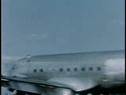 Airplane propeller and fuselage in flight over landscape, 1940s film style