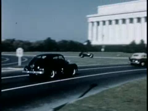 Classic car driving past the Lincoln Memorial in Washington, 1940s film style