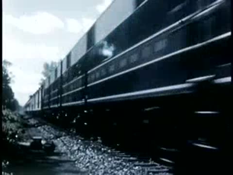 Streamlined diesel locomotive traveling fast on tracks, 1940s film style