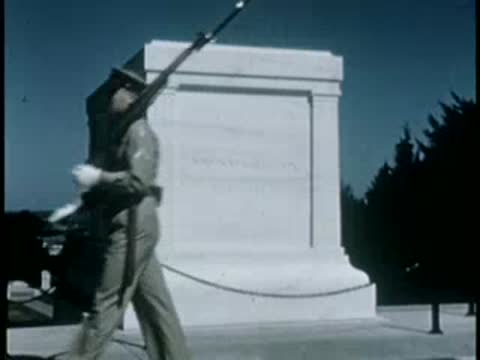 Guard in uniform marching past marble monument