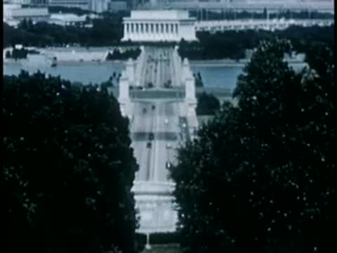 Aerial or high-angle tracking shot of a bridge leading toward Washington D.C.
