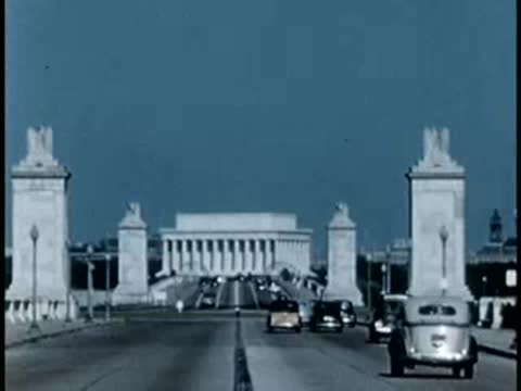 Medium shot of traffic driving across the Memorial Bridge toward the Lincoln Memorial.