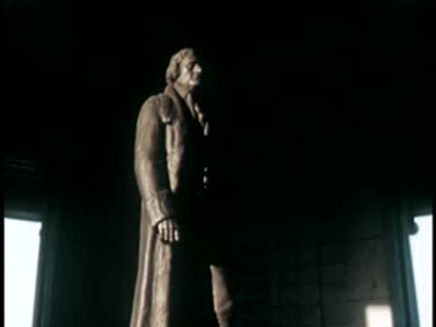 Close-up of a bronze standing statue inside a memorial building, 1940s.
