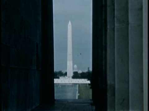 Shot looking through massive stone columns toward the Washington Monument in the distance.