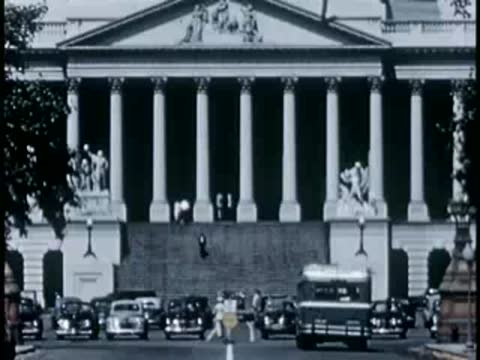 Medium shot of cars parked at the base of the U.S. Capitol steps, 1940s.