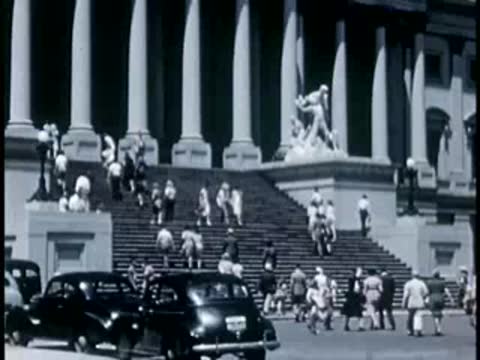 Medium shot of visitors walking up the front steps of the U.S. Capitol.