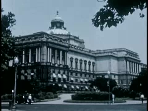 Medium shot of a neoclassical government building surrounded by trees, 1940s.