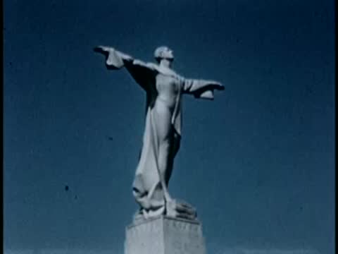 Statue of a robed figure with outstretched arms against a clear sky