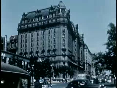 Large historic stone apartment building with cars on the street
