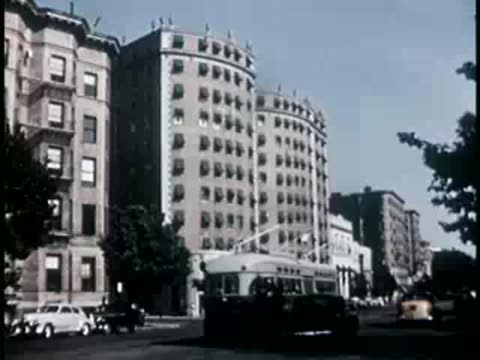 Urban street scene with tall apartment buildings and a passing bus
