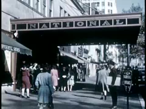 Entrance canopy of the National theatre with people walking on the sidewalk