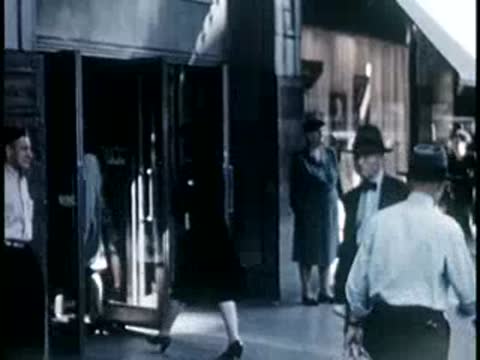 People entering a storefront with large glass windows and awnings, 1940s fashion.
