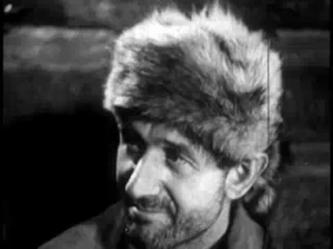 man wearing a fur hat smiling indoors by candlelight