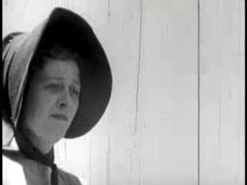 Close-up of a woman in a dark bonnet looking forward outdoors