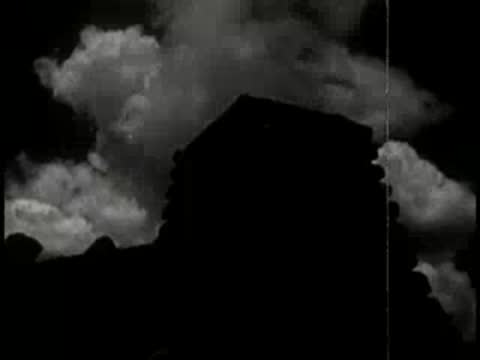 A dark silhouette of a structure against stormy clouds.