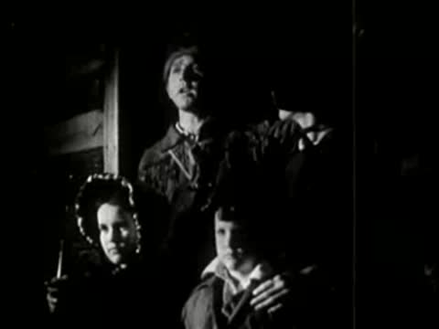 A family standing together looking upwards inside a darkened room.