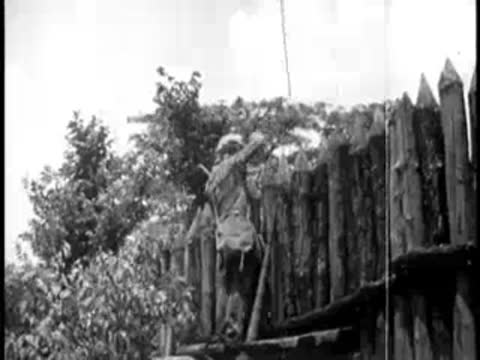 Pioneer working on the construction of a tall wooden stockade wall.