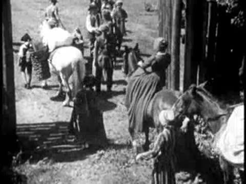 Busy fort yard with people, horses, and cattle moving about.