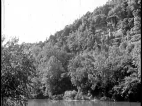 Static view of dense forested hills alongside a river or water source