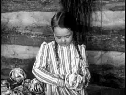 Young girl holding and working with yarn inside a cabin.