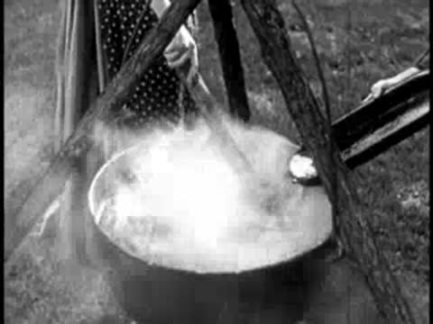 steam rising from a large cauldron outdoors with a wooden framework