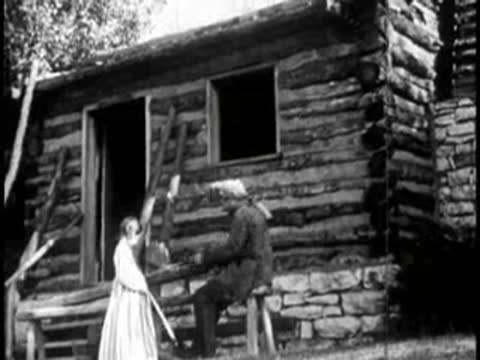 a girl and a man working outside a rustic log cabin building