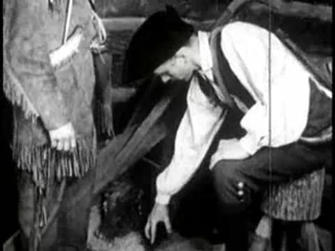 a man working with a wooden structure or tool inside a building