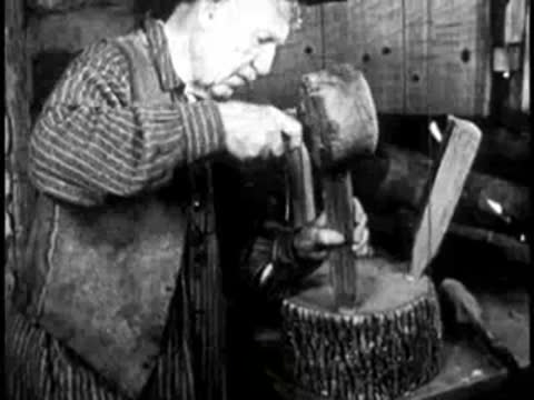 a man using a mallet to work on wooden pieces on a tree stump