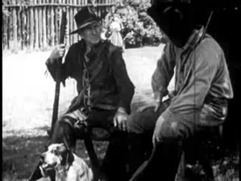 two men sitting outdoors together with a hunting dog at their feet