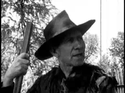 close-up of a man holding a rifle outdoors, looking to the side
