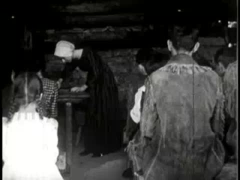 People gathering inside a rustic wooden cabin, historical interior