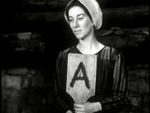 A woman holding up a wooden paddle with the letter A painted on it