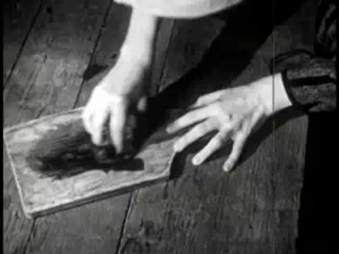 Hands erasing chalk on a wooden slate paddle with a cloth