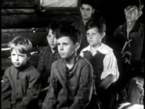 Young boys sitting attentively in a rustic log cabin classroom