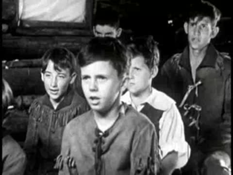 Young boys listening attentively inside a log cabin classroom