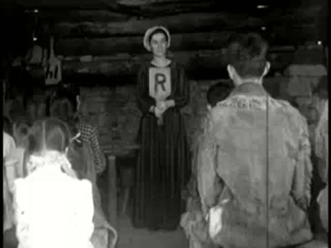 A woman holding a paddle with the letter R in a cabin