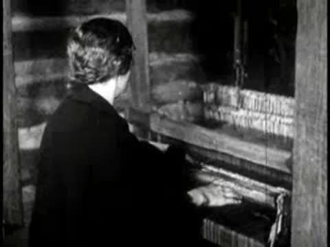 A woman playing a musical instrument inside a rustic cabin
