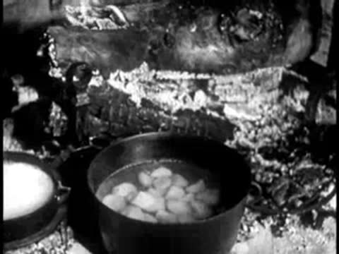 Close-up of food boiling in a pot over an open campfire