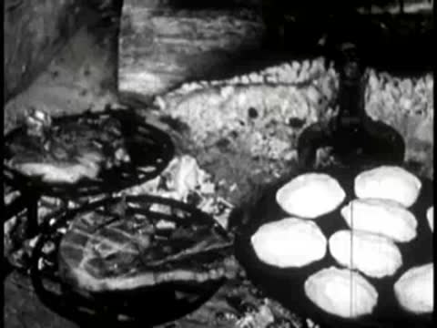 biscuits baking in a round griddle over an open fire