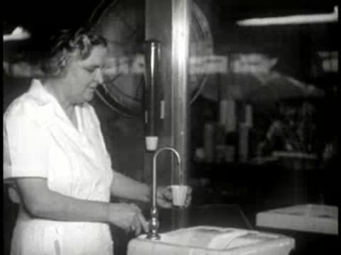 woman filling a cup from a water dispenser in a workplace