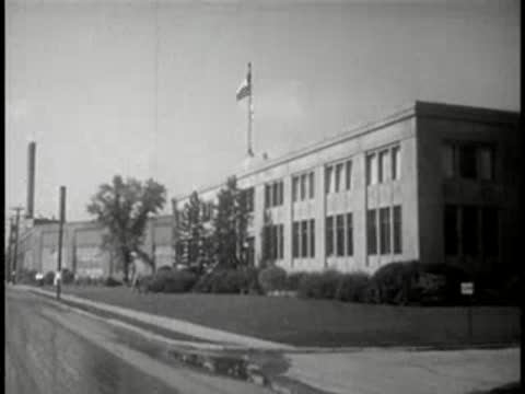 Exterior shot of a large modern industrial building with a flagpole on a sunny day