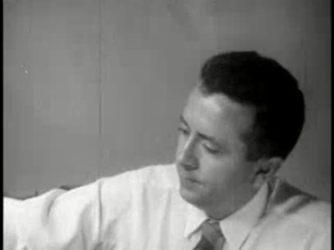 Man sitting at office desk, looking away and then talking on the telephone