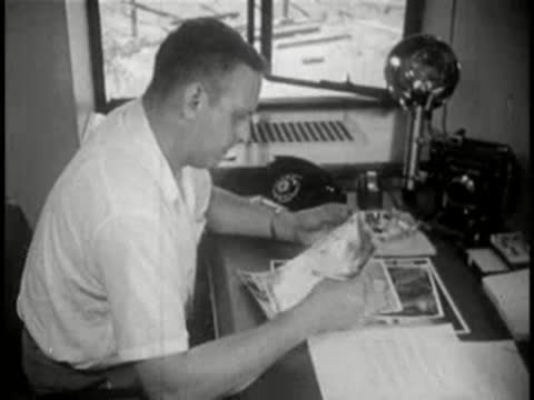 Man sitting at desk in an office, looking through pages of a magazine