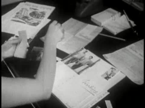 Close-up of hands arranging photographs and documents on a desk with inkwell