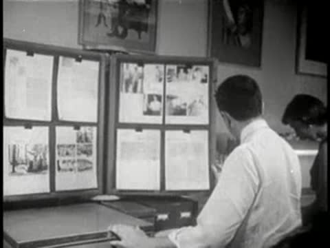 Man and woman standing in an office, pinning layout pages onto display boards