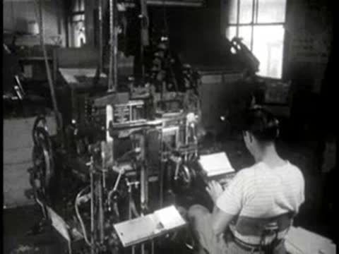 Woman operating complex industrial printing machinery in a factory print shop