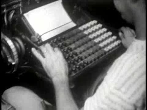 Close-up of a worker operating a specialized mechanical typesetting keyboard machine